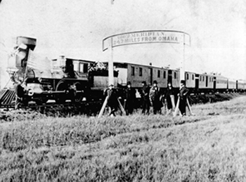 Black and white photo of a train with people standing in front 