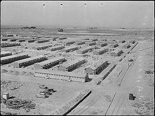 Black and white photo of the Minidoka Relocation Center. Rows of small rectangular buildings