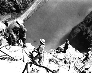 Black and white photo of workers drilling holes 