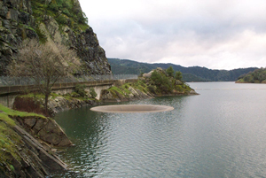 Photo of Lake Berryessa. A road winding around a mountain next to the water