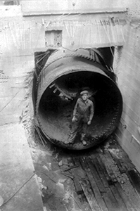 Black and white photo of someone standing in front of a large pipe