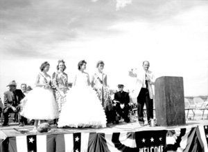 Black and white photo of four women and one man standing on an outdoor stage 