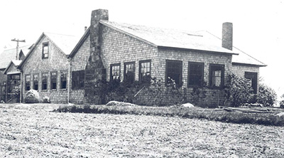 Windows surround the perimeter of a low, rambling house in a black and white image. Windows surround the perimeter of a low, rambling house in a black and white image.