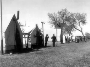 Black and white photo of rangers standing in front of large tents 