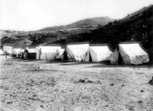 Black and whit photo of large tents with mountains behind them 