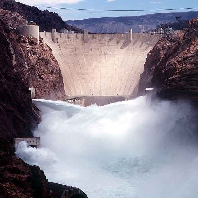 Large Dam and two jets of water pushing out of large red rocks 