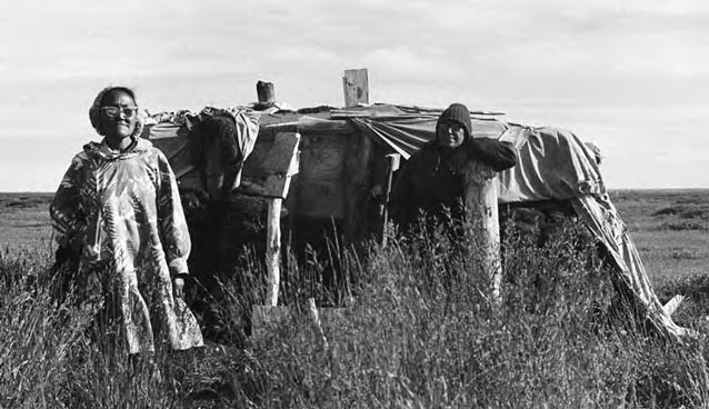 Women standing in front of a sod house. Women standing in front of a sod house.