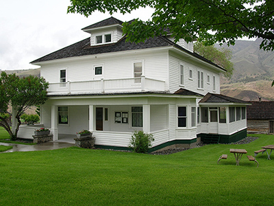 two story rectangular main house at the Cant Ranch, with a porch along the ground level