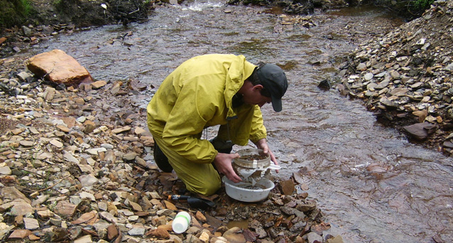 Man collecting sediment in a stream bed Man collecting sediment in a stream bed