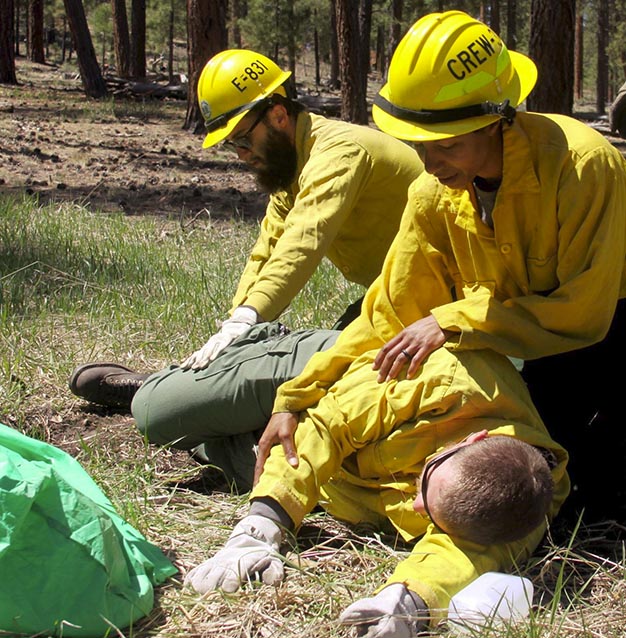 Firefighters assess an unresponsive crew memeber during a simulation Firefighters assess an unresponsive crew memeber during a simulation