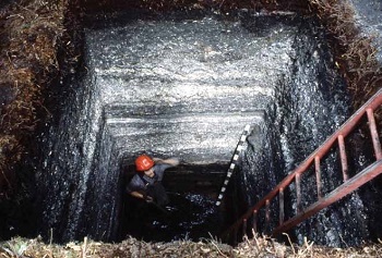 man in a deep square excavation site