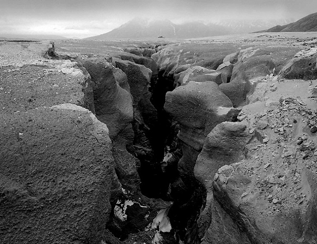 black and white photo of a creek througha snow bridge