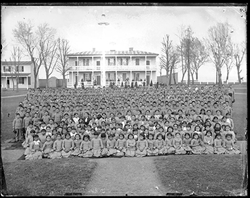 A group of over 100 Native American students standing and facing camera at Carlisle Indian School