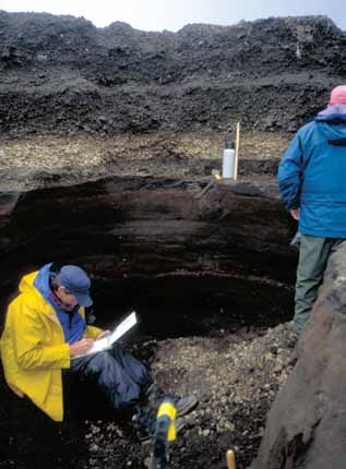 two men look at a wall of ash deposits