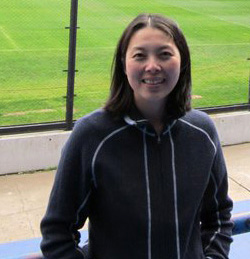 Woman in dark jacket with green grass behind her