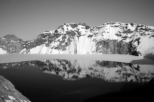 black and white photo of a mountain ridge reflected into a caldera lake