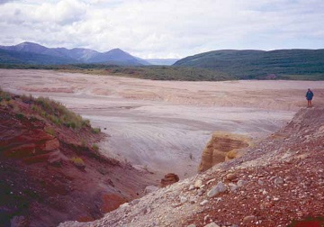 red moraines with a man standing at the top of a pile far away red moraines with a man standing at the top of a pile far away
