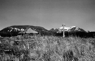 historic photograph of a cross in a field with mountains in the background historic photograph of a cross in a field with mountains in the background