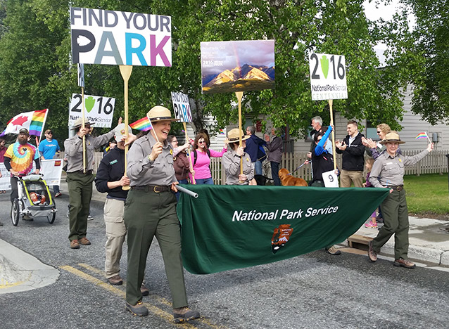 Employees walk in parade holding signs Employees walk in parade holding signs