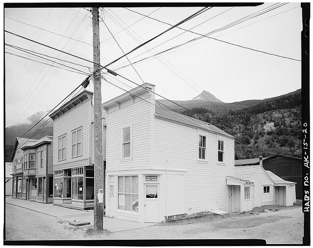 A black and white photo of three buildings along a street. A black and white photo of three buildings along a street.