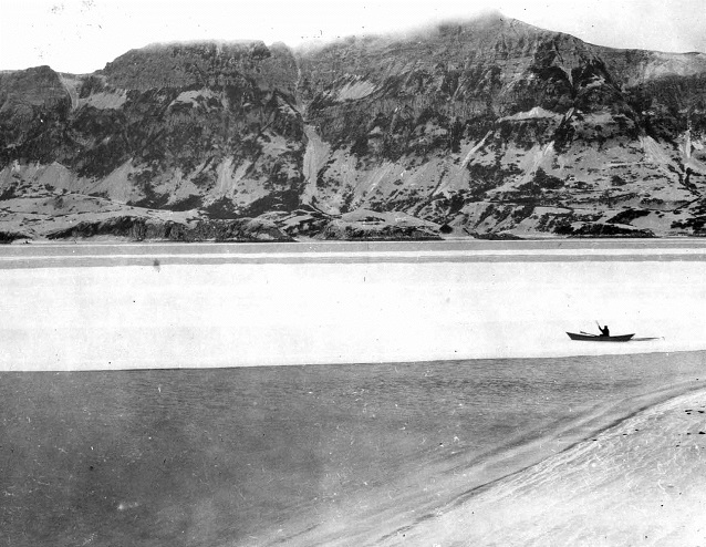 black and white photo of a man in a boat in a bay