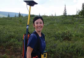 woman holding GPS unit in shrub vegetation