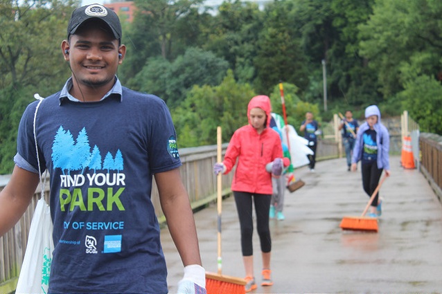 Volunteers carrying shovels walking across a bridge