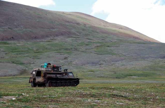 a tracked vehicle traveling across a tree-less landscape a tracked vehicle traveling across a tree-less landscape