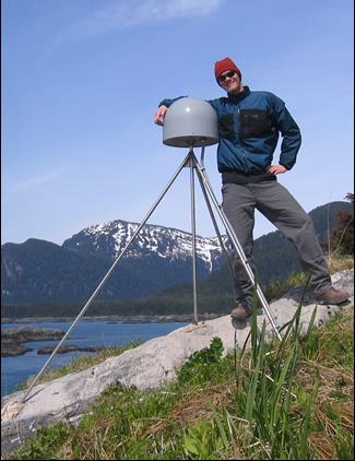 man stands next to GPS station on top of a tripod man stands next to GPS station on top of a tripod