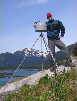 man stands next to GPS station on top of a tripod