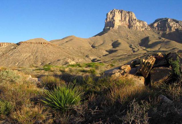 Sun-lit hills and towering rock formations under a clear blue sky at Guadalupe Mountains NP