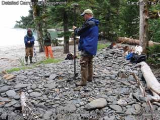 people stand on a rocky shore with GPS data collection equipment