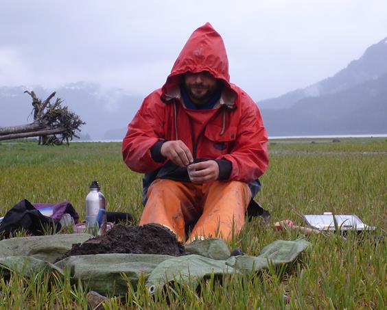 man in red raincoat collects soil