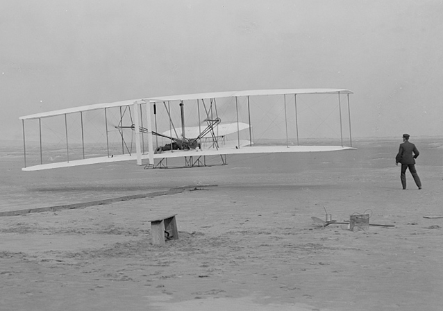 First flight, Orville at the controls, Wilbur running alongside- Kitty Hawk, 1903