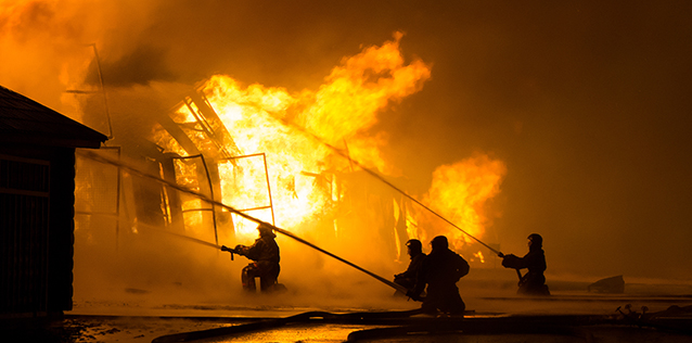 Firefighters putting out a large building fire at night.