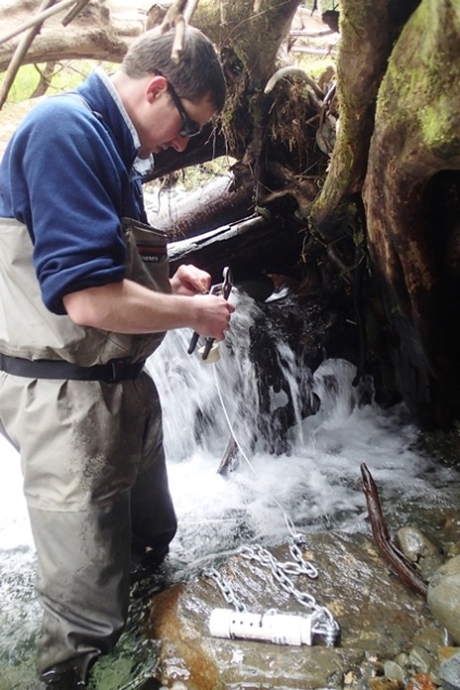 scientist installs temperature sensor to a stream
