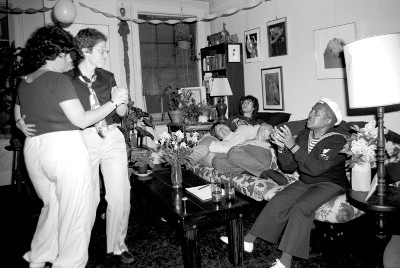 People dancing and lounging on a couch in a living room for a birthday party People dancing and lounging on a couch in a living room for a birthday party