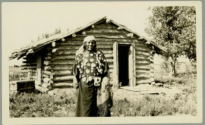 A man standing in front of a small wood cabin A man standing in front of a small wood cabin