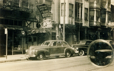 Row of buildings, including 440 Broadway, with cars parked along the street in front