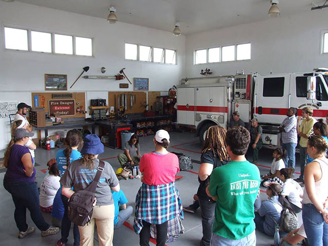 A park firefighter shows students the contents of her fireline pack.