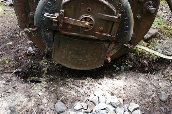 The front of an iron boiler with slumping earth beneath it