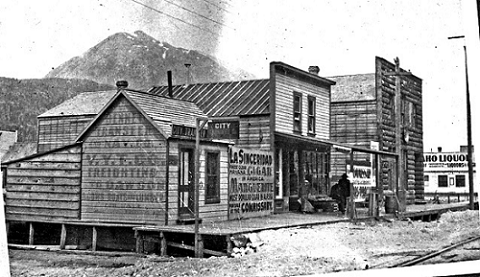 Black and white photo of several buildings along an unpaved road