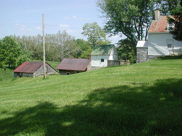 The roofs of buildings seen beyond a swatch of bright green grass, showing the rolling terrain. 