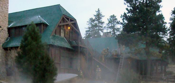 Exterior lodge during fire with evergreen trees nearby. Exterior lodge during fire with evergreen trees nearby.