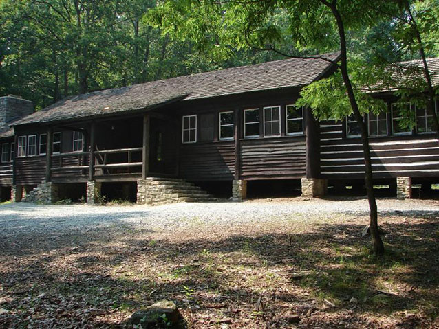 A long, low log building has a porch and stone pillar foundations. A long, low log building has a porch and stone pillar foundations.