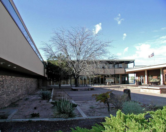 Rectangular buildings surround an open courtyard, containing some benches, trees, and plantings. Rectangular buildings surround an open courtyard, containing some benches, trees, and plantings.