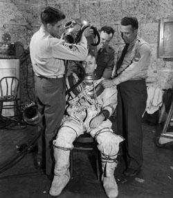 Ray H. Wright putting on a diving suit to protect him from high pressure, temperature and noise 