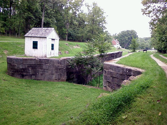 Grass grows in what was once the canal waterway, marked by the stone-lined lock and the towpath Grass grows in what was once the canal waterway, marked by the stone-lined lock and the towpath