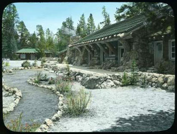 Historic image of stone-lined, curving pathway to the right of a rustic lodge