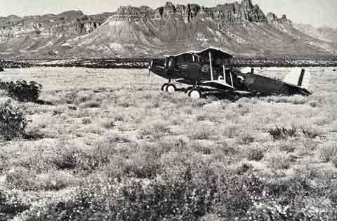 historic black and white image of Douglas Airplane in an open field